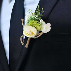 a boutonniere with white flowers and greenery is worn on a man's suit