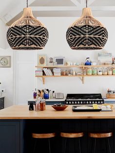 two hanging lights above a kitchen island with stools in front of it and shelves on the wall