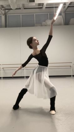 a woman in a ballet pose with her arms up and one leg raised, while the other