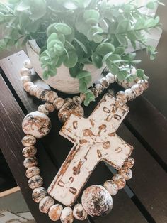 a wooden cross sitting on top of a table next to a potted plant