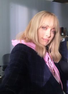 a woman with blonde hair is wearing a suit and pink tie in an office setting