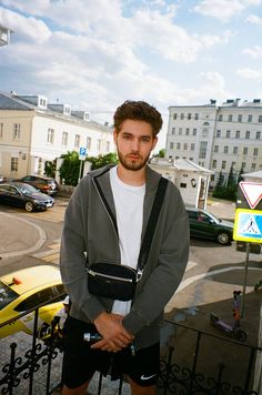 a man standing in front of a fence with his hands on his hips and looking at the camera