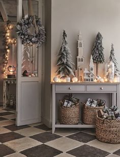 christmas decorations are displayed in baskets on the floor next to a table with candles and wreaths