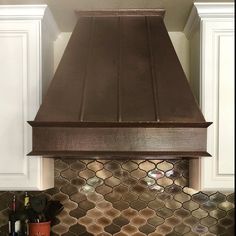 a stove top oven sitting inside of a kitchen next to a counter with wine bottles on it