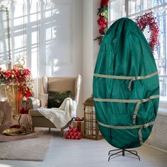 a large green egg sitting on top of a wooden floor next to a christmas tree