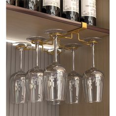 several wine glasses are lined up in front of bottles on a shelf with gold trim