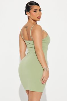 a woman in a green dress with her back turned to the camera and wearing high heels