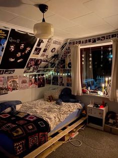 a bed room with a neatly made bed next to a window and posters on the wall