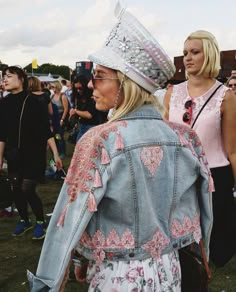 a woman wearing a denim jacket and a crown on her head at a music festival