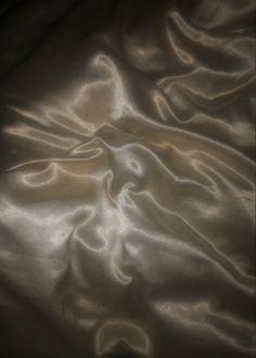 an image of a bed that is made up with white sheets and satin material on it