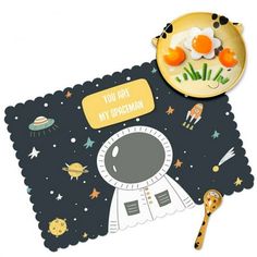 an astronaut themed placemat with eggs on it next to a plate and spoons