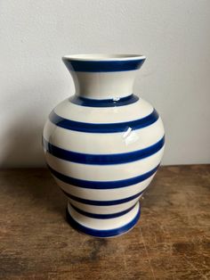 a white and blue vase sitting on top of a wooden table