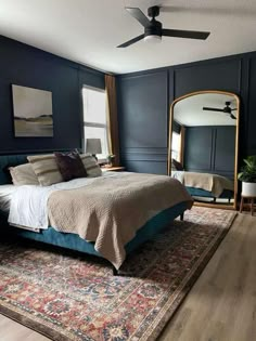 a bed sitting on top of a wooden floor next to a large mirror in a bedroom