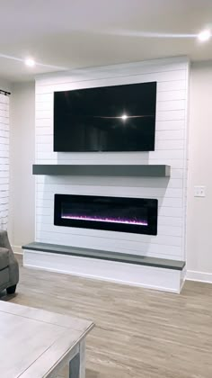 an empty living room with a fireplace and flat screen tv on the wall above it