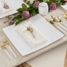 the table is set with flowers and gold cutlery, napkins and place settings