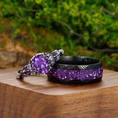 two purple and black bracelets sitting on top of a wooden table next to each other