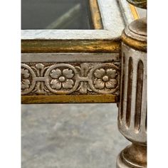 an ornate gold and silver table with a glass window in the center, sitting on concrete