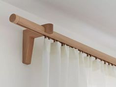 the curtain rod is made from wood and has white curtains hanging on it's side