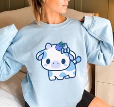 PLEASE NOTE:  This is a UNISEX sweater.  If you want an oversized look then consider ordering up a size. This cute blueberry cow sweater will look adorable on you!  Makes for a great kawaii gift for your loved ones as well. The collar is ribbed knit, so it retains its shape even after washing. There are no itchy side seams on these sweaters.  .: 50% cotton, 50% polyester .: Medium-heavy fabric (8.0 oz/yd² (271.25 g/m .: Loose fit .: Sewn-in label .: Runs true to size Oversized Kawaii Sweatshirt With Cartoon Print, Oversized Kawaii Cartoon Print Sweatshirt, Blue Long Sleeve Kawaii Sweatshirt, Cute Blue Sweatshirt With Graphic Print, Cute Oversized Blue Tops, Blueberry Outfit, Cow Merch, Blue Clothes Aesthetic, Cow Clothes