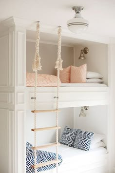 a white bunk bed with rope hanging from it's sides and pillows on the bottom