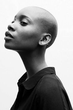 a black and white photo of a woman with shaved hair looking up to the side