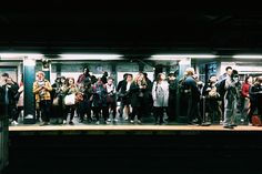 a group of people standing on top of a train platform next to eachother