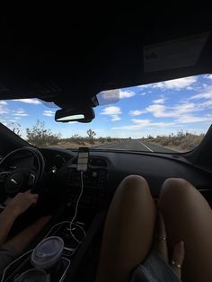 two people driving in the back seat of a car with their feet on the dashboard