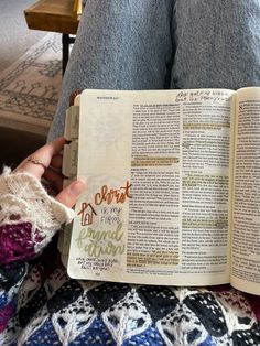 a person is reading a book on their lap and holding it in one hand with both hands