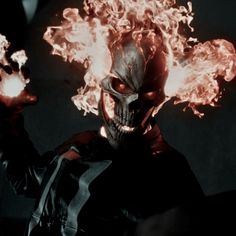 a man with flames on his face and hands in front of him, wearing a mask