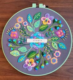 an embroidery project with flowers and the words create in white lettering on a purple background