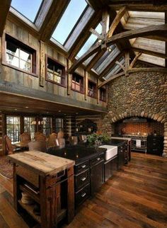 an open kitchen and living room with wood flooring, stone fireplace and vaulted ceiling