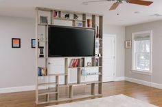 a living room with a large tv mounted to the wall next to bookshelves