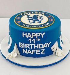 a blue birthday cake with white frosting and a chelsea crest on the top layer