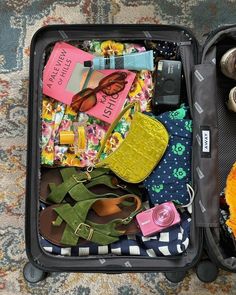 an open suitcase filled with clothing and other items sitting on the floor next to a stuffed animal