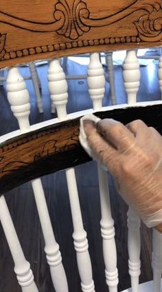 a person with a glove on their hand cleaning a wooden chair's spindles