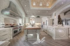 a large kitchen with white cabinets and an island in the middle of the room is lit by recessed lights