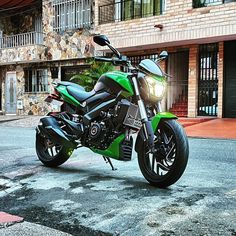 a green and black motorcycle parked in front of a building