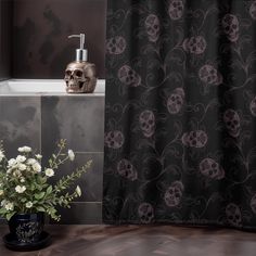 a skull is sitting next to a bathtub with flowers in the foreground and a black shower curtain behind it