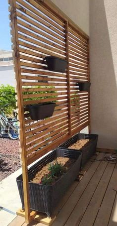 a wooden trellis with plants growing in it on top of a deck next to a building