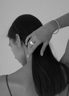 a woman with her hand on the back of her head while she is combing her hair