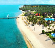 an aerial view of a resort on the beach with blue water and palm trees in the foreground