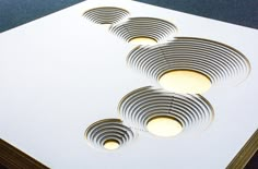 four circular cut out pieces of paper sitting on top of a white surface with holes in the middle