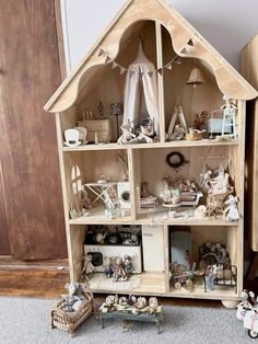 a white doll house with lots of toys on the floor and in front of it