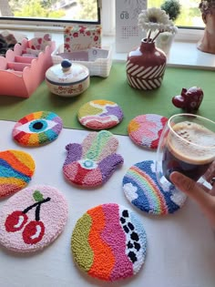 a person is holding a glass in front of some decorated coasters