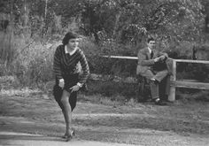 an old black and white photo of two people sitting on a bench