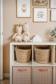 two stuffed animals sitting on top of a white book shelf next to baskets and pictures