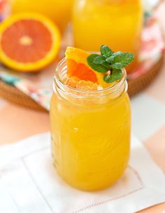 two mason jars filled with orange juice and garnished with mint