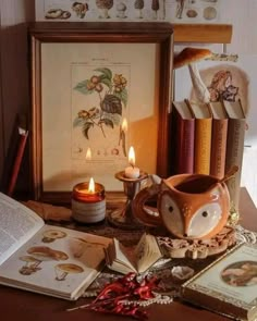 an arrangement of books, candles and other items on a table in front of a framed photograph