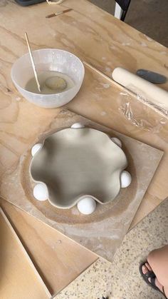 someone is making something out of clay on a table with other tools and supplies around it