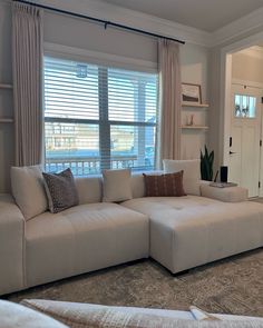 a living room filled with furniture next to a window covered in blinds and drapes